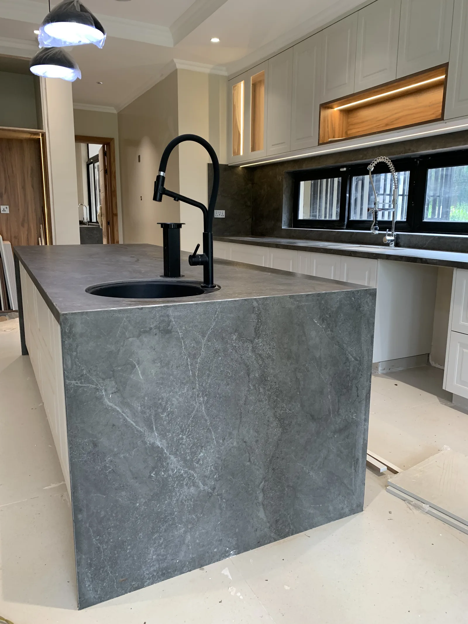 A dark stone kitchen island with an integrated sink, against white cabinetry