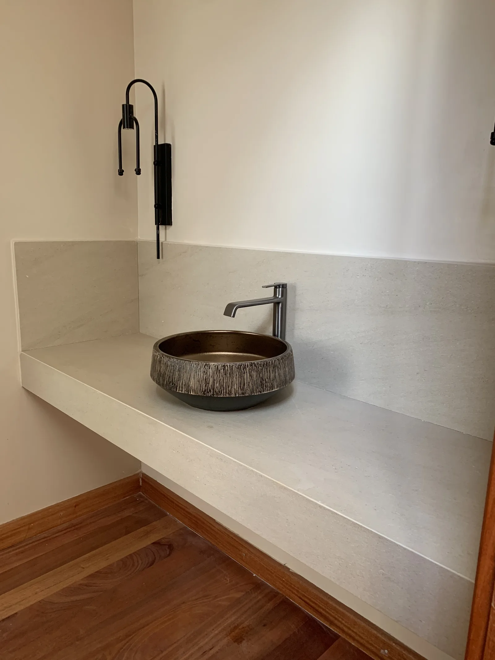 A floating stone vanity shelf with a bronze vessel basin