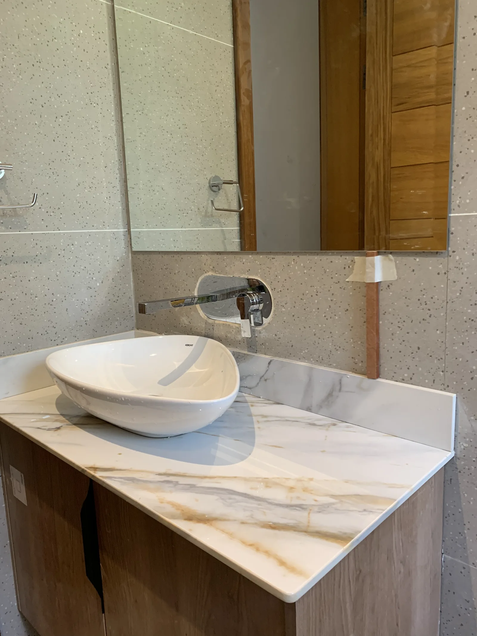 A vanity counter in gold veined stone with a vessel basin, on a timber cabinet